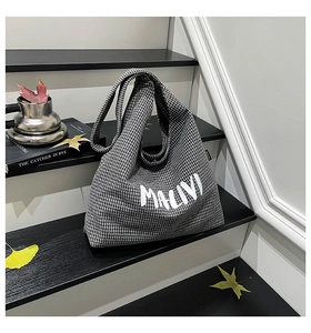 Detailed shot of a black and white checkered canvas tote bag with artistic letter printing