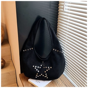 Detalle de bolso hobo de ante negro con tachuelas de estrella de metal sobre madera