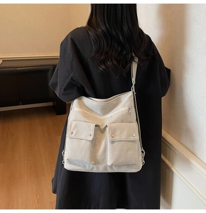 Detailed back view of a beige canvas tote bag with functional pockets and silver zippers