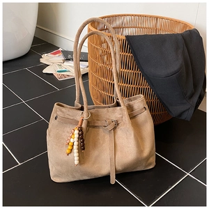 Detailaufnahme der khakifarbenen Wildleder-Tote mit Holzperlen-Anhänger und Metallschnalle
