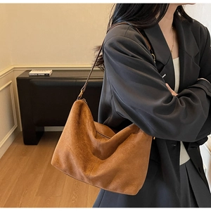 Borsa hobo in camoscio marrone indossata da una modella, stile quotidiano con texture morbida