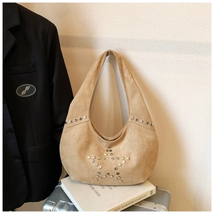 Detalle de bolso hobo de ante beige con estrellas de remaches de plata y textura suave