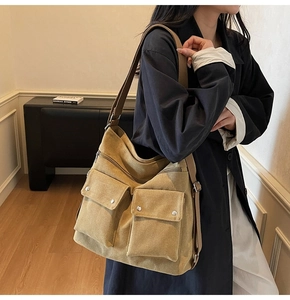 Detail shot of khaki canvas crossbody bag featuring utility pockets and metallic buckles