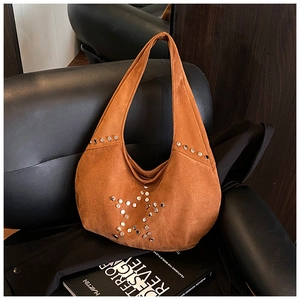 Detalle del bolso hobo de ante marrón naranja con remaches de estrella plateados en un asiento