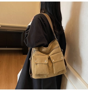 Detail view of the khaki canvas bag showing dual front pockets with metal snap buttons