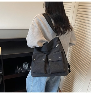 Detail view of large canvas shoulder bag with functional flap pockets and metal snaps