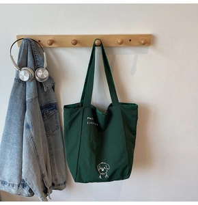 Detail of green canvas tote bag featuring dog illustration and Hello LittleDog text print