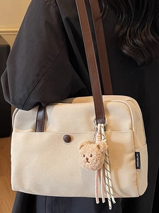 Beige canvas tote bag with dark brown leather straps and a cute plush bear charm decoration