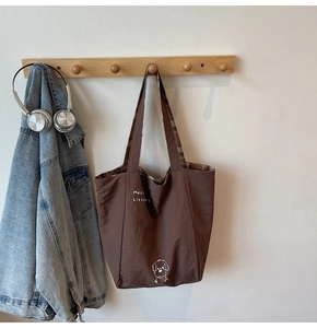 Detail of a large canvas tote bag with a dog print and brown checkered inner lining