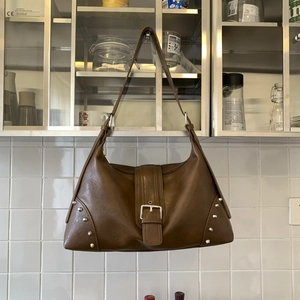 Dettaglio borsa vintage in pelle marrone con fibbia argento e borchie metalliche