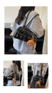 Glossy black Boston bag with buckle pockets and a brown poodle plush charm detail