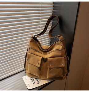 Detail of canvas tote bag showing front flap pockets with rivets and multiple zippers