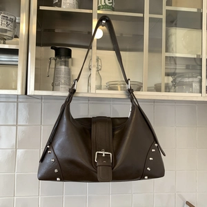 Dettaglio borsa hobo vintage marrone con fibbia argentata e decorazioni rivetti