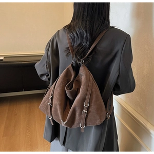Close-up of suede backpack showing brown texture, silver rings and adjustable buckle strap