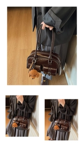 Detail of dark brown glossy PU leather boston bag with outer pockets and a teddy charm