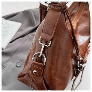 Detail of silver spring hook and durable stitching on a vintage brown leather bag