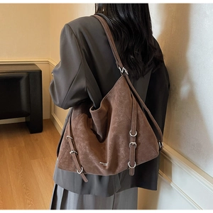 Detail of dark brown suede tote bag featuring silver buckles and vintage texture