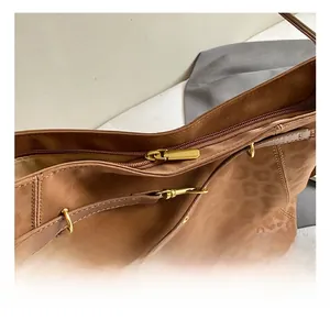Detail of leopard embossed brown leather tote showing gold metal zipper and stitching