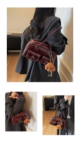Detail of burgundy glossy leather Boston bag with silver buckles and a cute teddy charm
