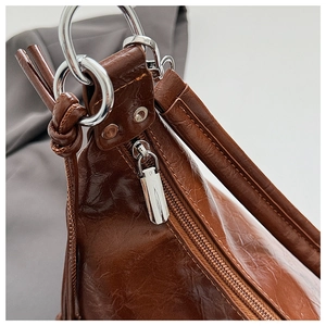 Detailed close-up of brown oiled leather texture with silver hardware and zipper