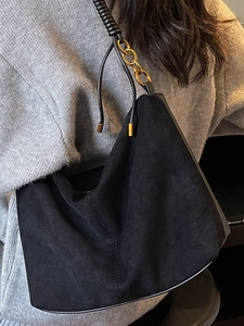 Borsa sottobraccio in camoscio nero con catena dorata e tracolla a spirale indossata dal modello
