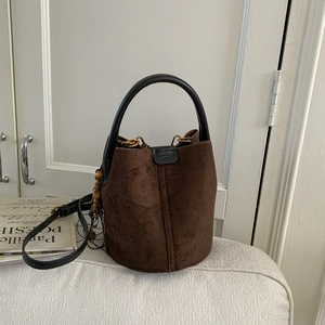 Close-up of vintage brown suede bucket bag featuring wooden bead charm and black handle
