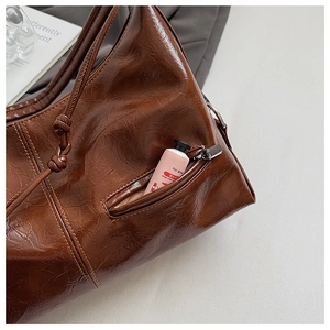 Detail view of brown leather tote bag with functional zipper pocket and vintage texture