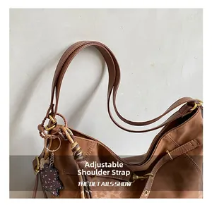 Detail view of brown faux leather tote with adjustable strap and leopard bear charm