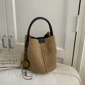 Close-up of brown suede bucket bag featuring ethnic floral bead charms and leather handle