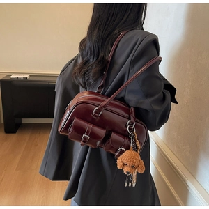Close-up of a glossy dark red patent leather shoulder bag with cute puppy plush charm