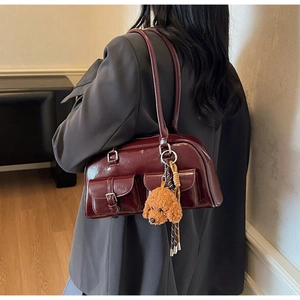 Detail view of burgundy patent leather Boston bag with dual pockets and teddy charm