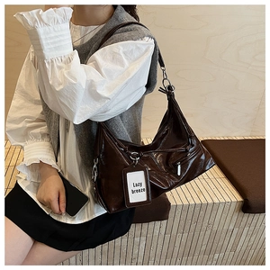 Detail of dark brown glossy patent leather tote bag with drawstring and side pocket