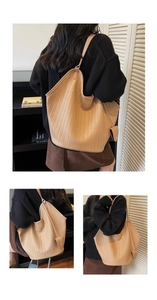 Détail d'un sac cabas tissé marron clair avec large bandoulière et pendentif décoratif en cuir