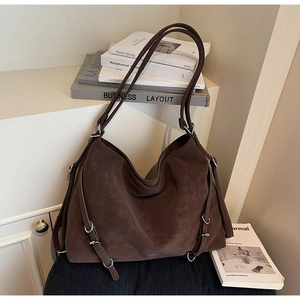 Close-up of vintage brown hobo bag featuring decorative leather straps and metal buckles