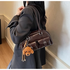 Detail view of dark brown patent leather shoulder bag with plush teddy bear charm