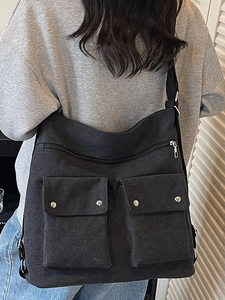 Black canvas crossbody bag with multiple pockets and adjustable strap shown on model