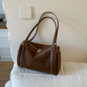Detail of vintage brown suede pillow bag with silver zippers on a white sofa