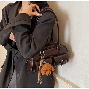 Detail view of coffee Boston shoulder bag with dual flap pockets and a plush dog charm