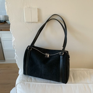 Close-up of matte black suede texture and dual silver zipper detail on vintage pillow bag