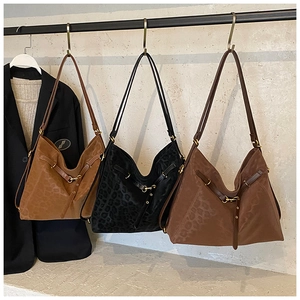 Three leopard print tote bags in camel, black and dark coffee on a display stand