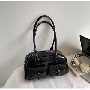 Glossy black faux leather boston bag with silver buckles in a lifestyle setting