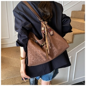 Close-up of brown leopard embossed tote bag with tassel and vintage bear charm