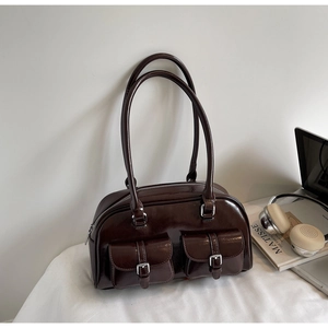 Detail of dark brown patent leather Boston bag with silver hardware and front buckled pockets
