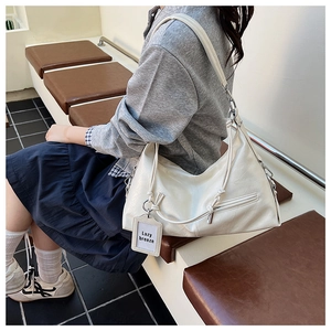 Detail view of off-white faux leather shoulder bag with textured surface and knotted strap