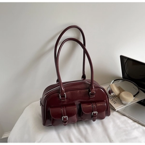 Detail view of burgundy leather shoulder bag featuring silver buckles and double front pockets