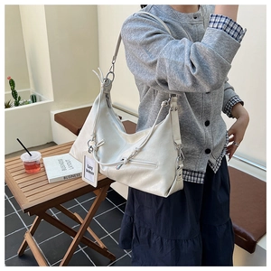 Detail view of cream white hobo bag with zipper and Lazy Breeze tag on a model