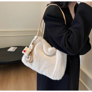 Dettaglio borsa a tracolla in peluche beige con ciondolo toast su giacca nera