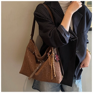 Detail of leopard print tote bag featuring braided tassel and floral bear pendant