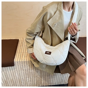 Close-up of a white quilted crescent shoulder bag with heart embroidery and pearl accent