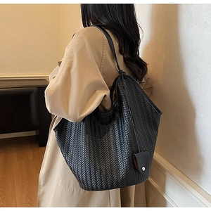 Détail d'un sac à bandoulière tressé noir avec texture en V et anses fines en cuir